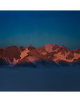 Snow-covered Arctic mountains glowing with the deep orange-pink light of alpenglow.