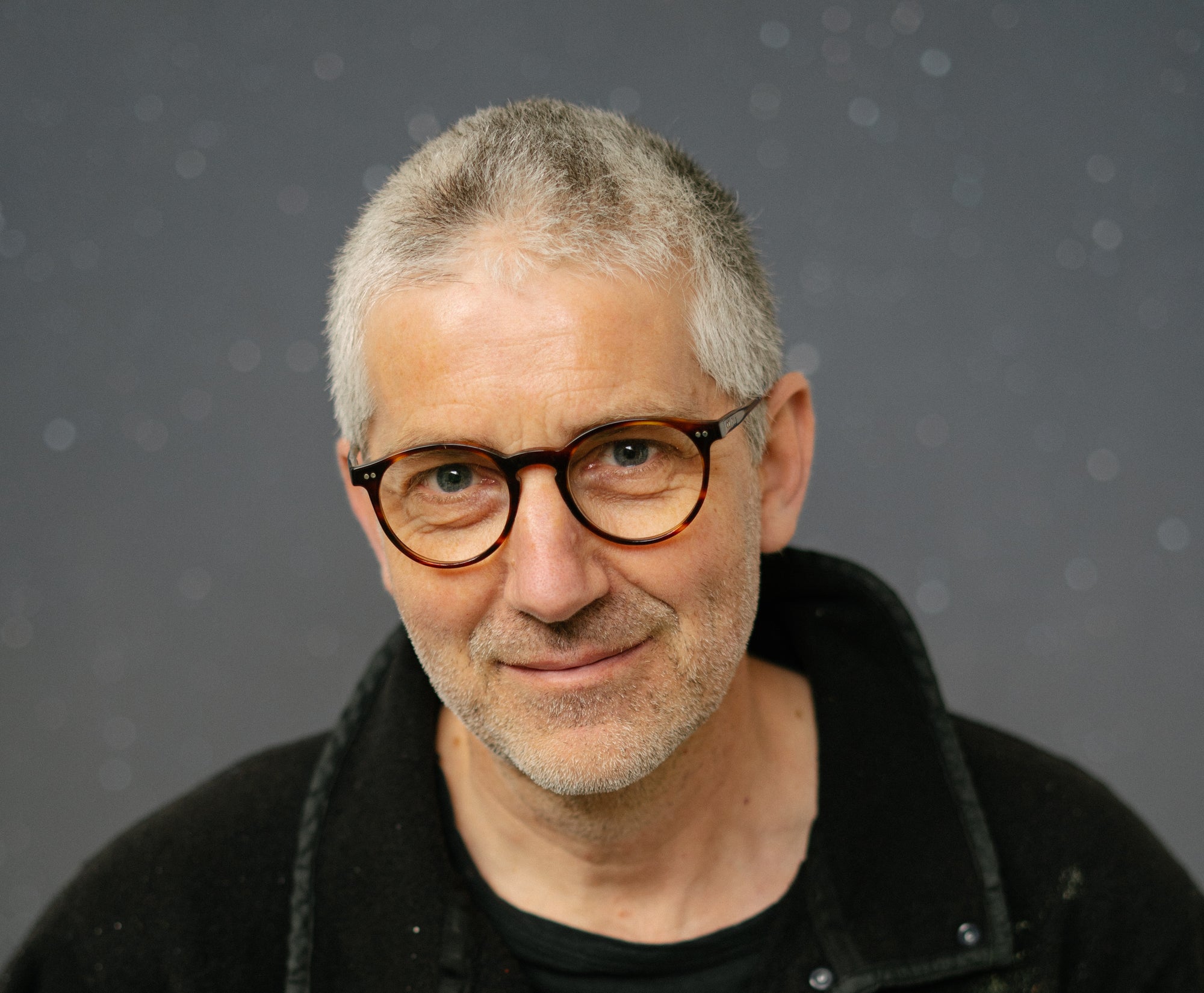 Portrait of artist Nicholas Jones, smiling gently and looking into the camera.