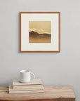 The screen print “Alone in the Mountains,” displayed above a wooden bench with a book and cup, evokes solitude and space in a high, remote place.