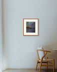 Framed art print of "Aurora Reflected", displayed in a minimalist space lit by soft filtered light, with a wooden chair nearby. Shown here in the size medium.