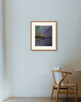 Framed art print of "Aurora Reflected", displayed in a minimalist space lit by soft filtered light, with a wooden chair nearby. Shown here in the size large.