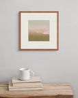 Framed above a wooden bench with a book and cup, “Bloom” brings a soft energy, hinting at the quiet unfolding of nature.