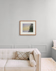 Framed art print of 'Evening Rainbow, Lake Nellim, Finland", shown in an elegant, minimalist room with a classic sofa and a window seat. Displayed here in the size medium.