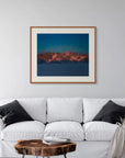 Framed art print of "Mountains and Alpenglow" by Nicholas Jones, shown in a serene pale grey room with a white sofa and soft grey cushions. Displayed here in the size extra-large.
