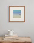 The print “Sea Dreams” hangs above a wooden bench with a book and cup, suggesting starlit twilight or underwater realms.