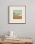 Framed above a wooden bench with a book and cup, “The Thinning Air” suggests altitude, stillness, and the clarity of high places.