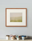 Framed art print of "This Beautiful Light", displayed above a wooden surface holding four antique patterned china cups. Shown here in the size small.