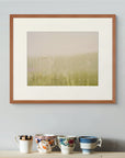 Framed art print of "This Beautiful Light", displayed above a wooden surface holding four antique patterned china cups. Shown here in the size medium.